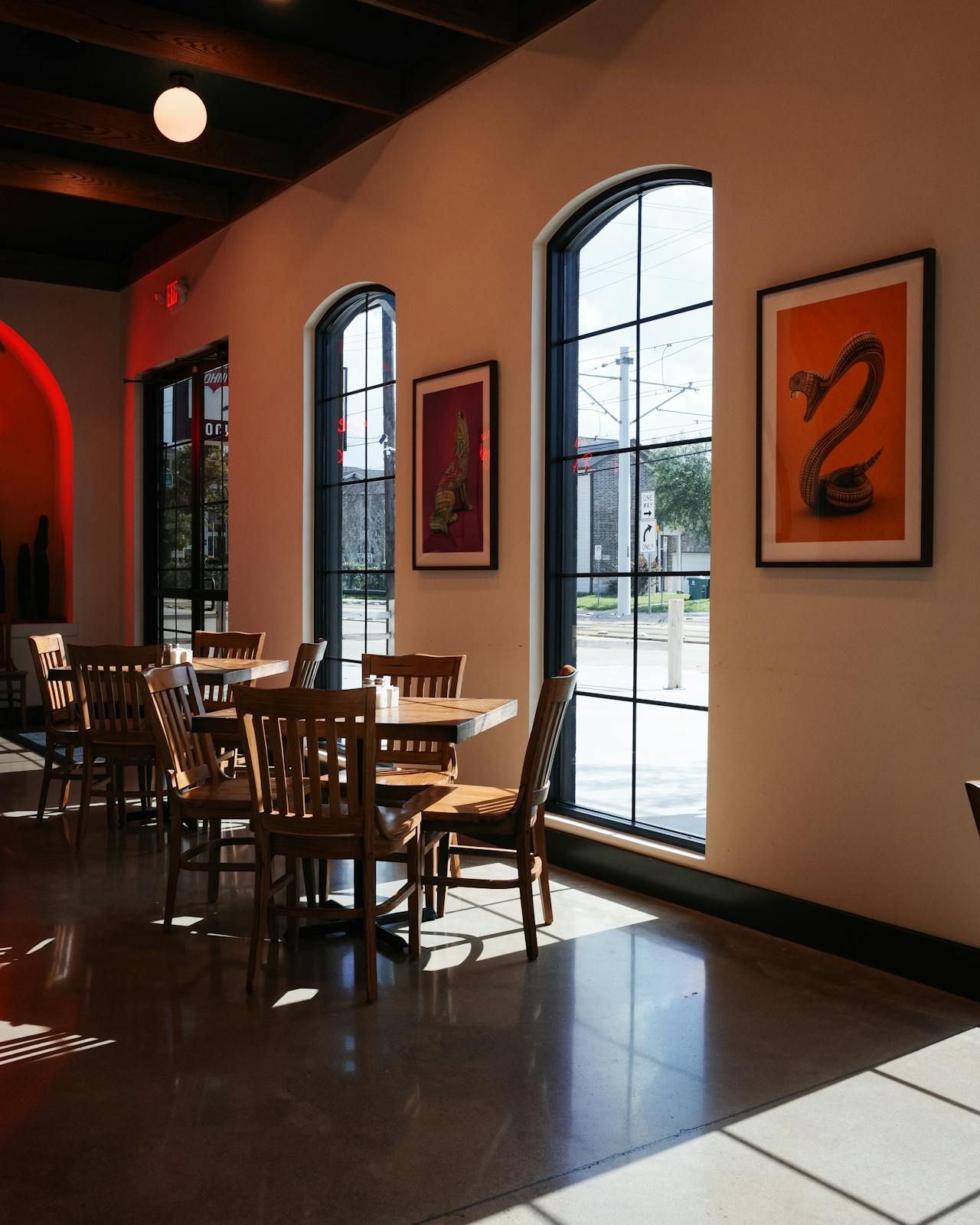 Sunlit restaurant interior with wooden furniture and artistic décor, ideal for dining.